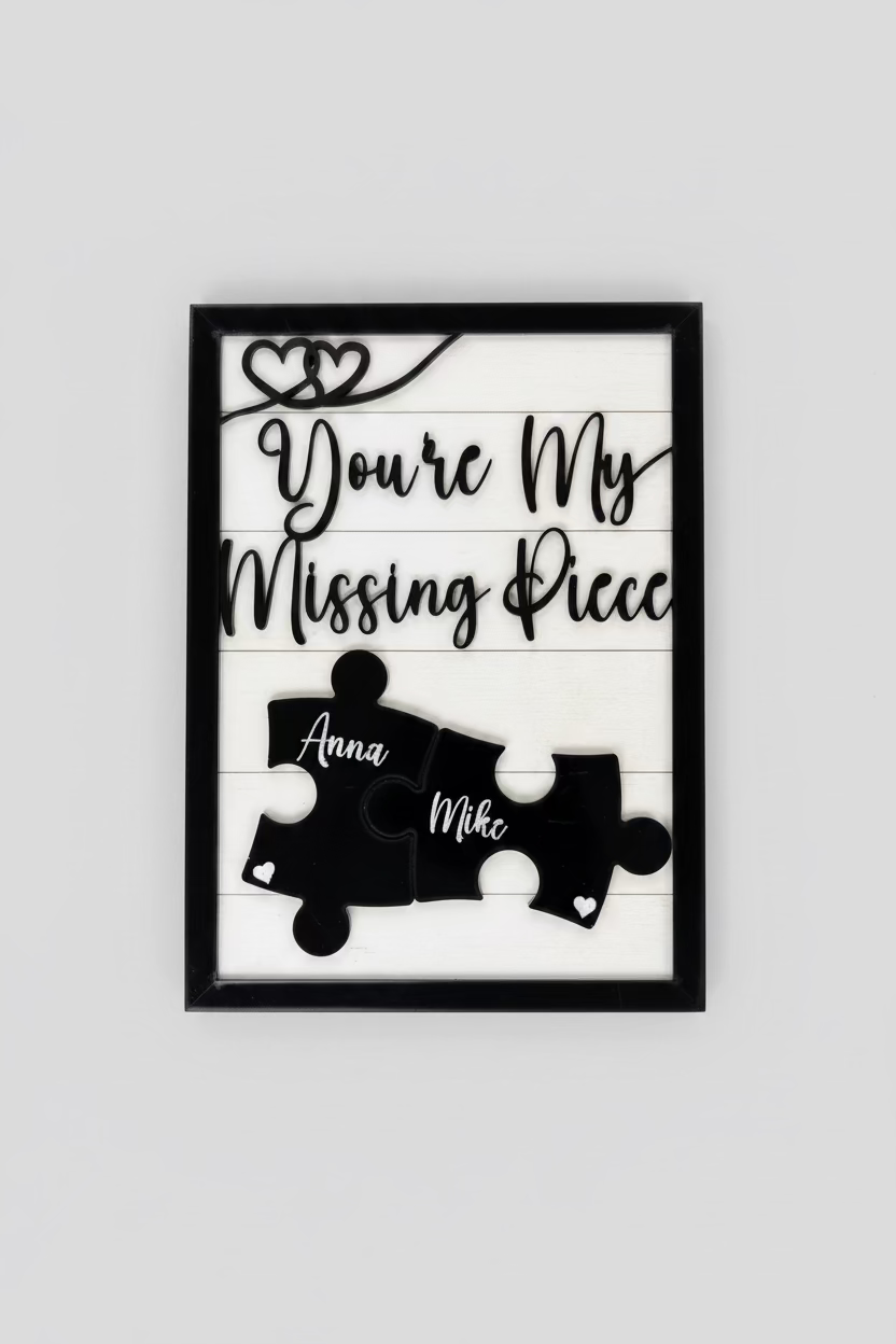 A close-up of a custom wooden sign with the phrase "You're My Missing Piece" in stylish black cursive font. Two black puzzle pieces, engraved with the names "Anna" and "Mike," interlock at the center, symbolizing love and connection. The sign has a black border with heart-shaped accents and rests on a rustic wooden surface. A perfect personalized gift for couples, anniversaries, or Valentine's Day.