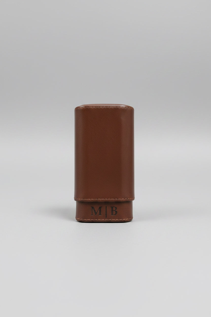 Brown leather humidor with M|B monogram on wooden surface