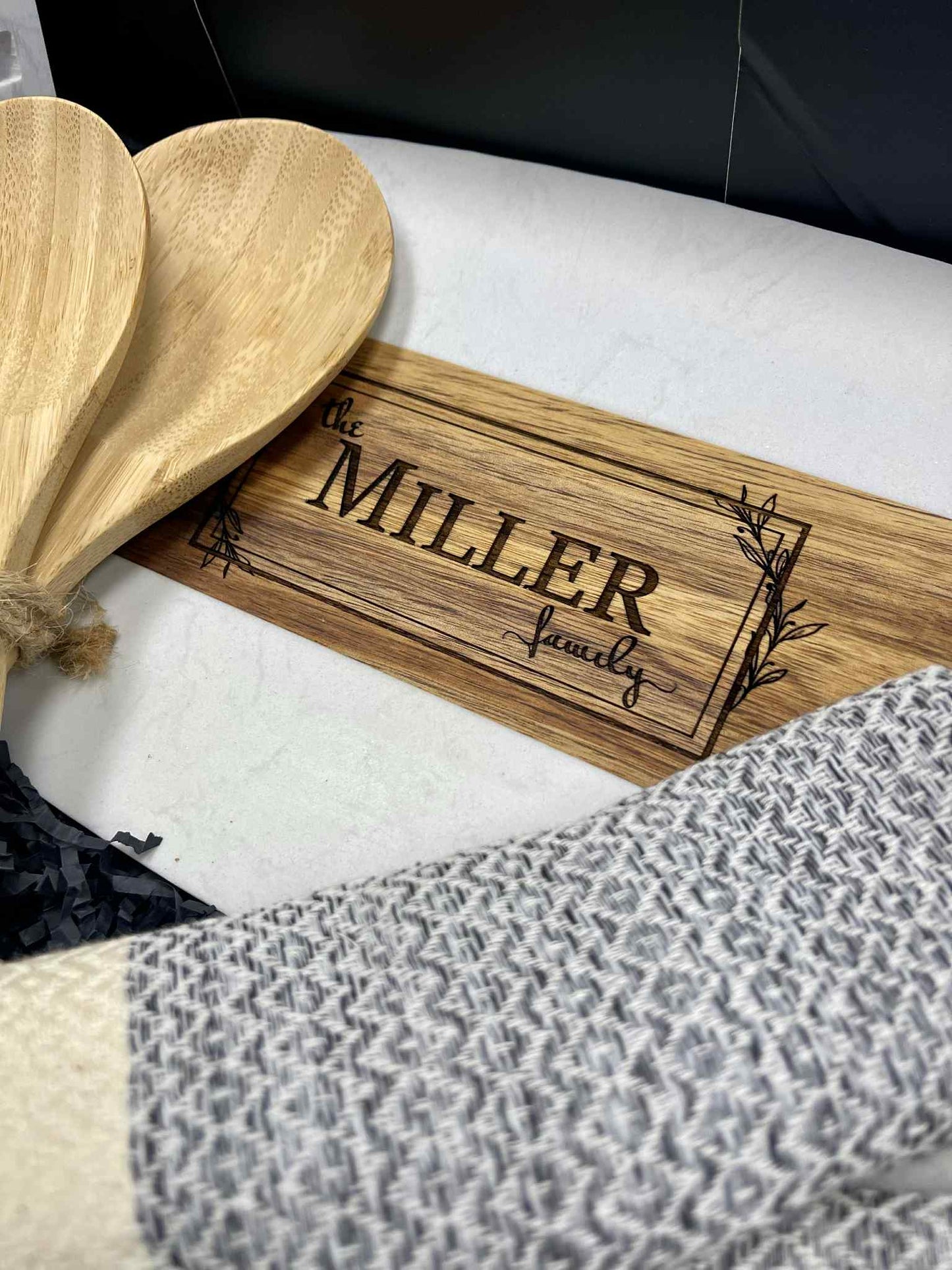 Wooden cutting board with 'The Miller Family' engraving on a white surface.