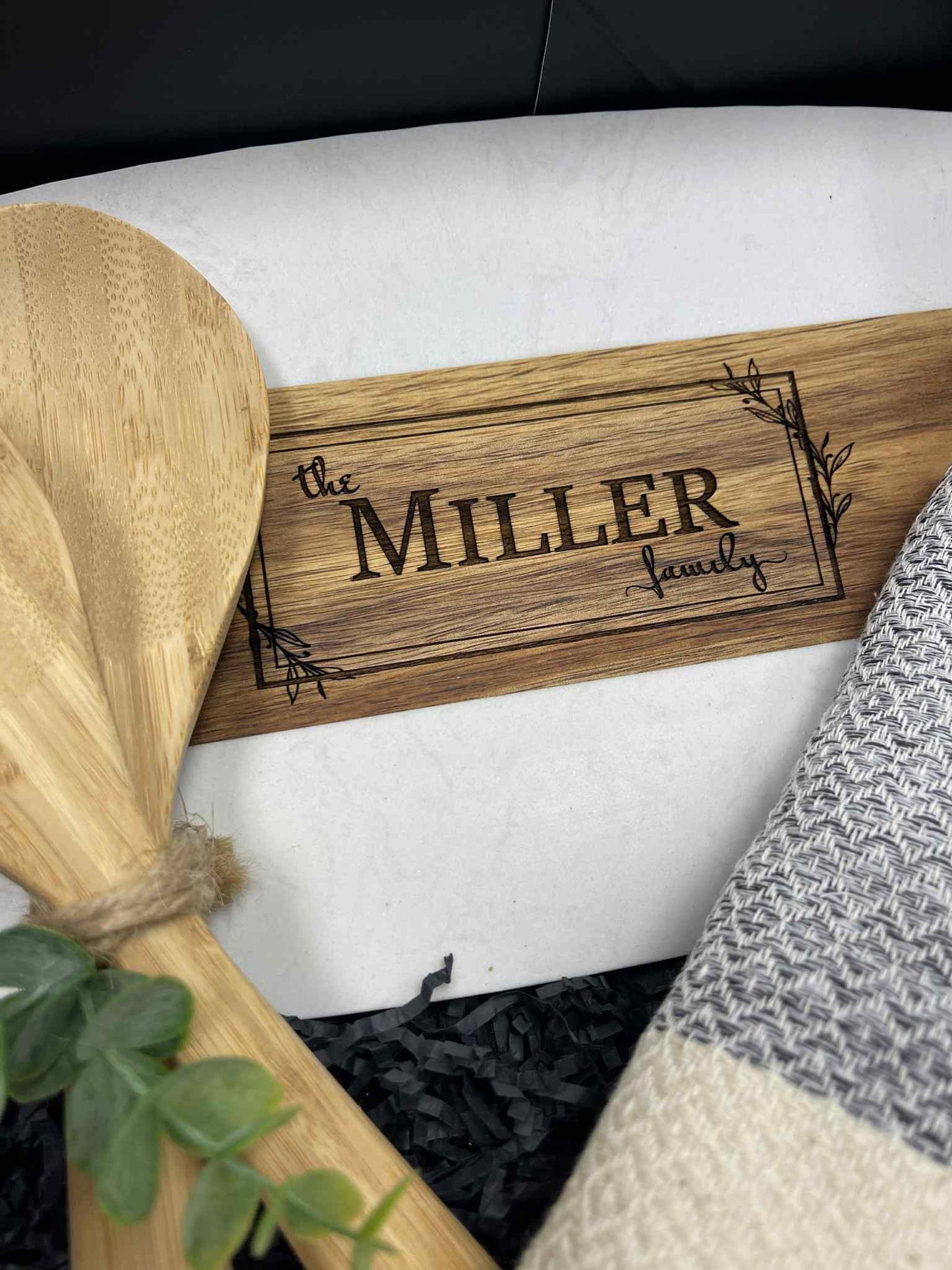Wooden sign with 'the MILLER family' engraving on a white surface.