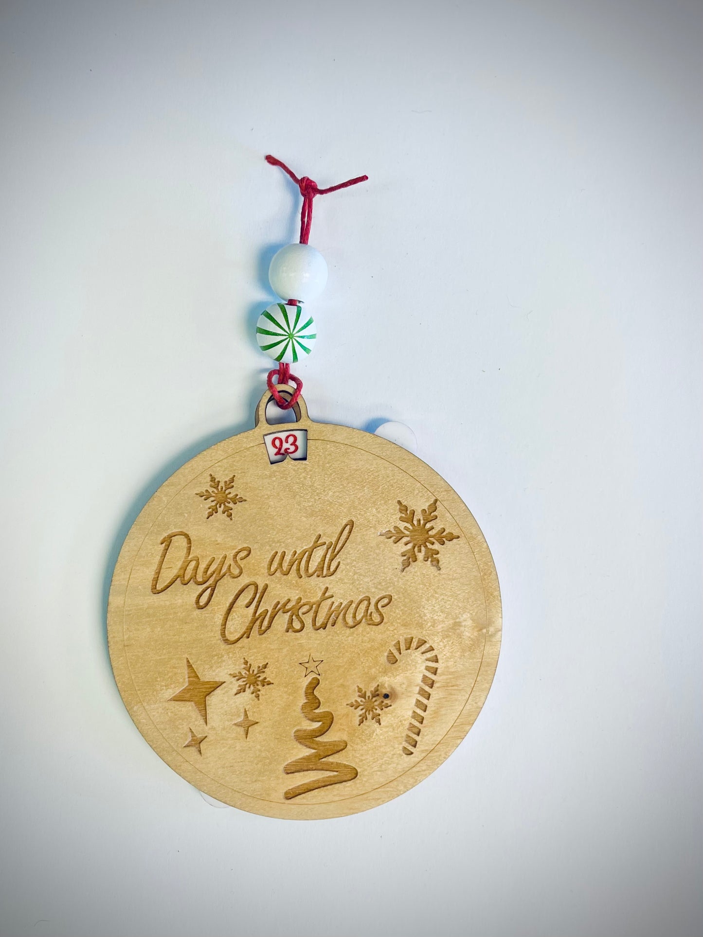 Wooden Christmas countdown ornament with engraved text, festive beads, and holiday icons
