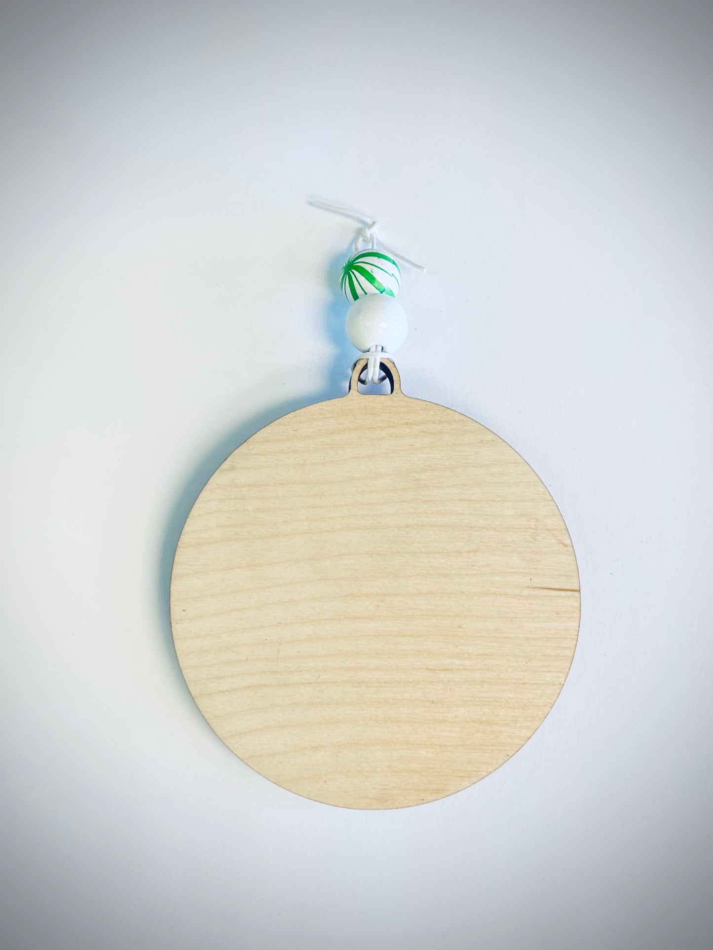 Blank wooden round ornament with two white beads on a white background