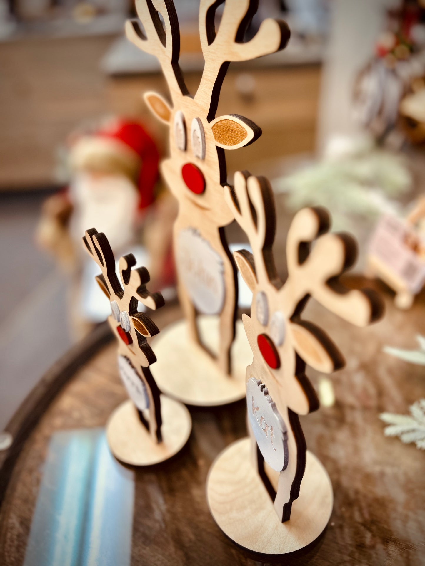 Wooden reindeer table decorations with red noses on a rustic wooden surface