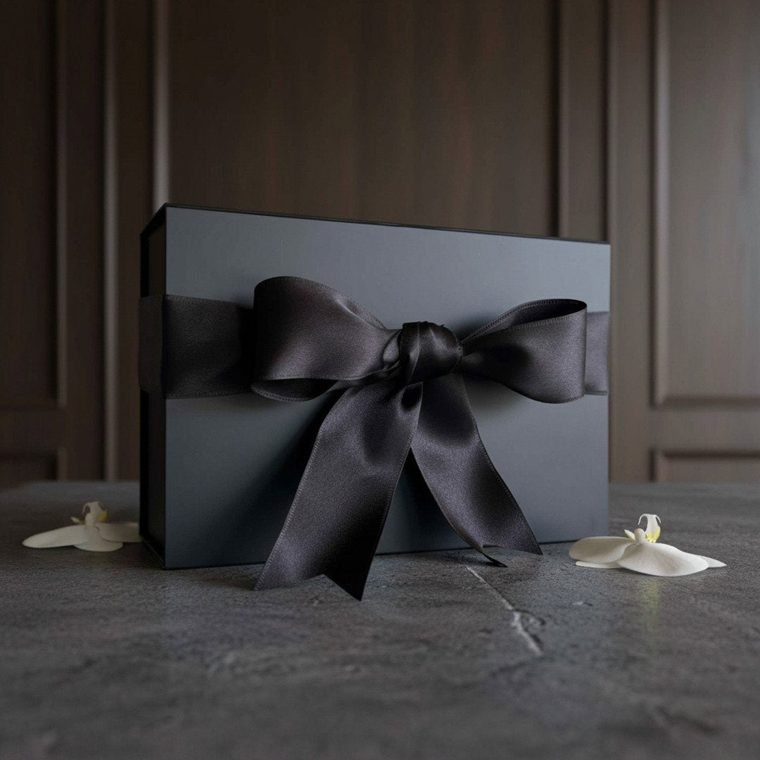 Sleek black gift box with satin black ribbon bow on light surface, kitchen set packaging