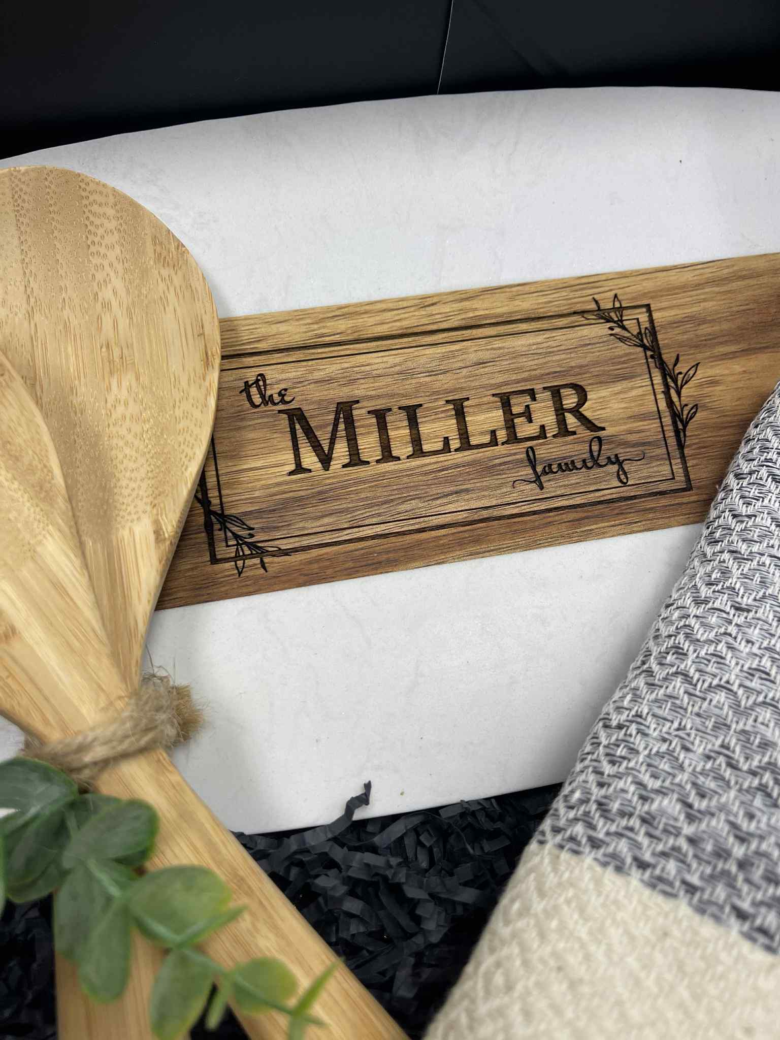 Wooden sign with 'the MILLER family' engraving on a white surface.