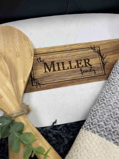 Wooden sign with 'the MILLER family' engraving on a white surface.