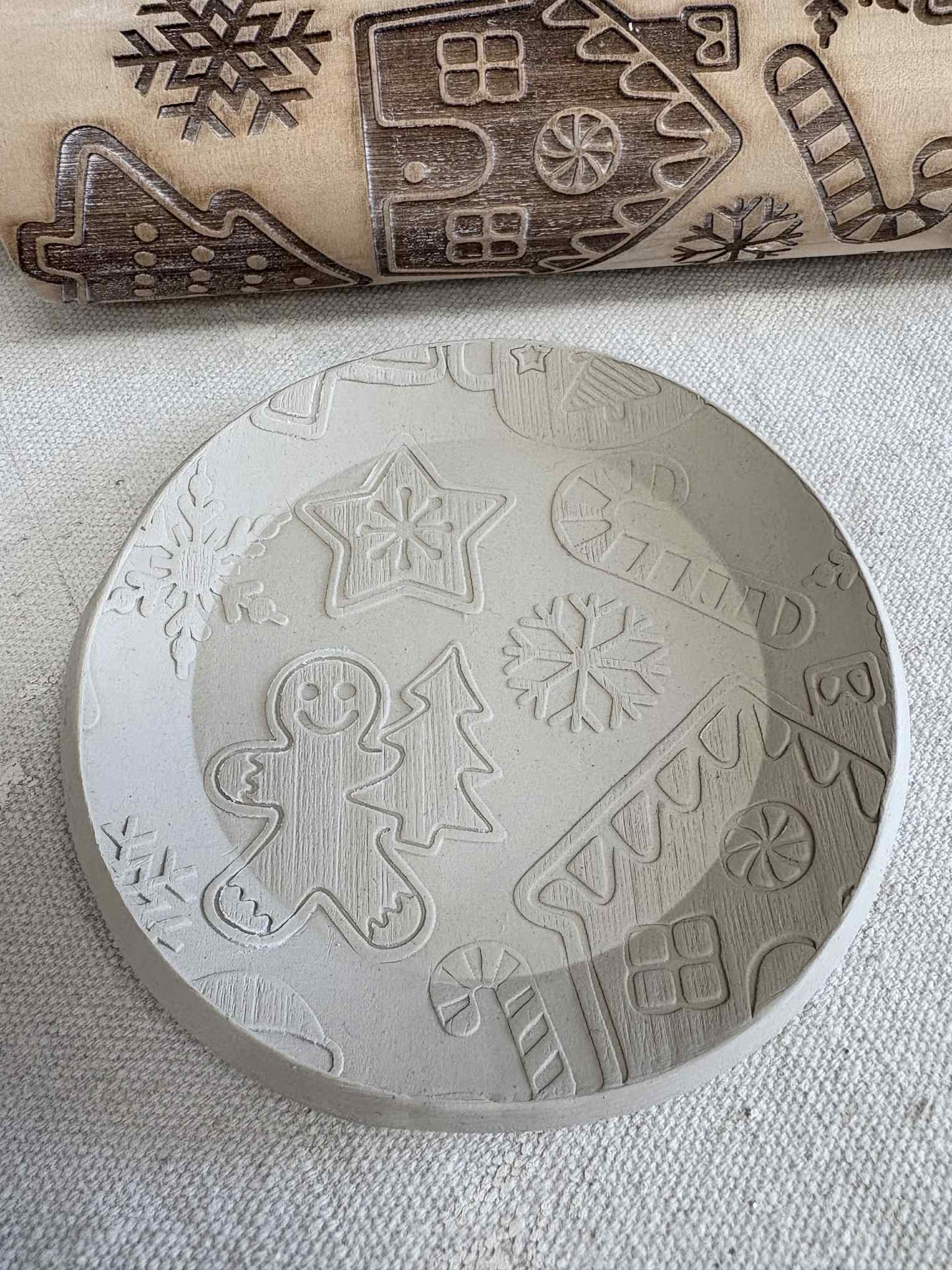 Embossed Christmas rolling pin with gingerbread, snowflake, and candy cane designs on dough