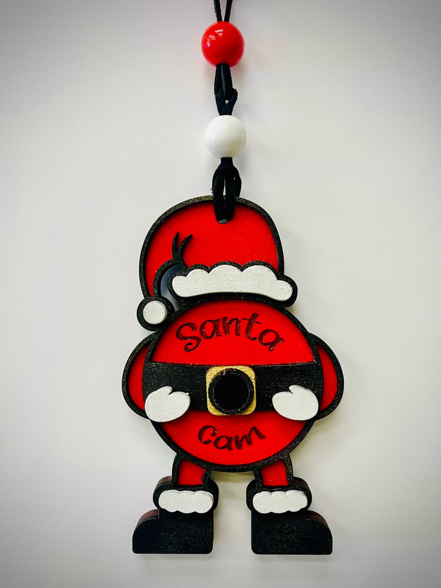 Santa Cam ornament with red and white beads, shaped like Santa, hanging against a white wall