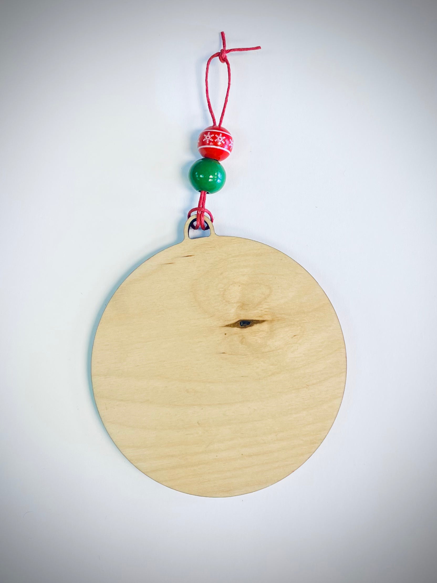 Blank wooden Christmas ornament with red and green beads on a red string