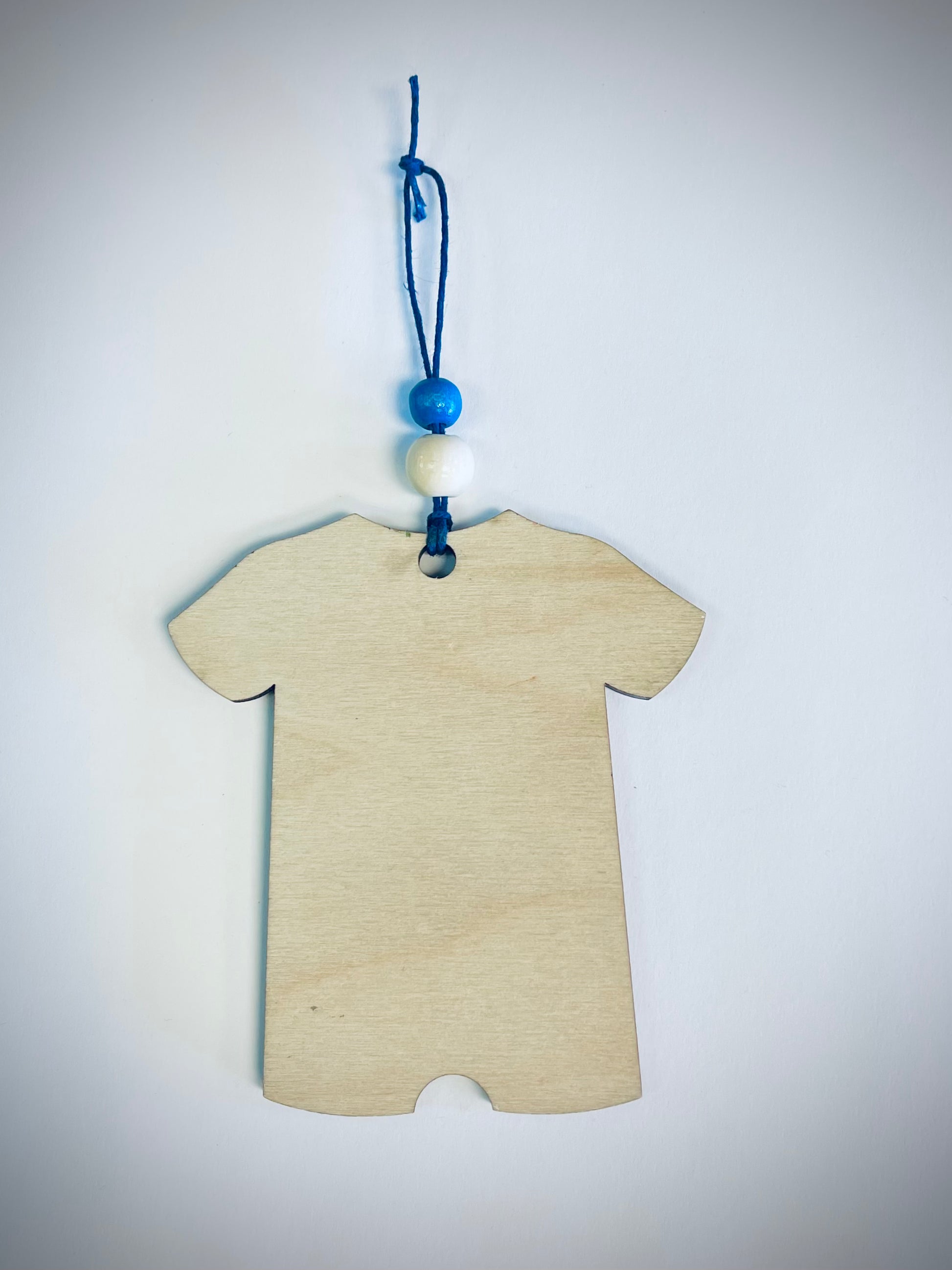 Blank wooden onesie ornament with blue and white beads on a blue string, white background