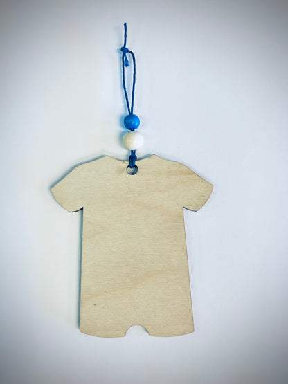 Blank wooden onesie ornament with blue and white beads on a blue string, white background