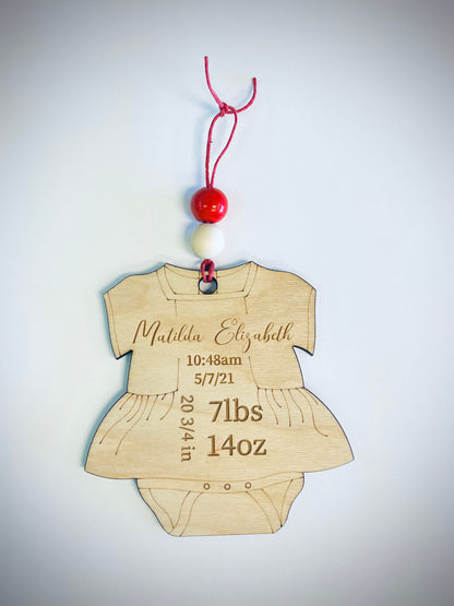 Wooden baby onesie ornament with red and white beads, personalized birth details engraved