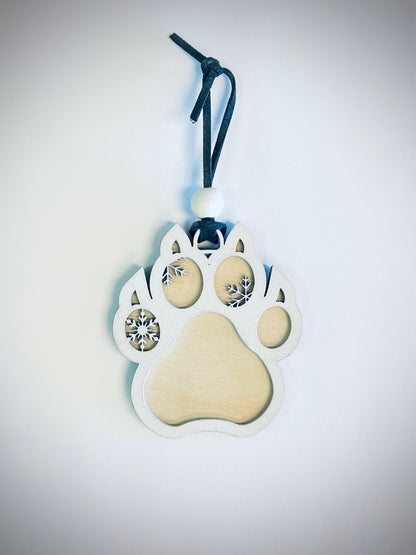 Wooden cat paw ornament with snowflake cutouts and black string on white background