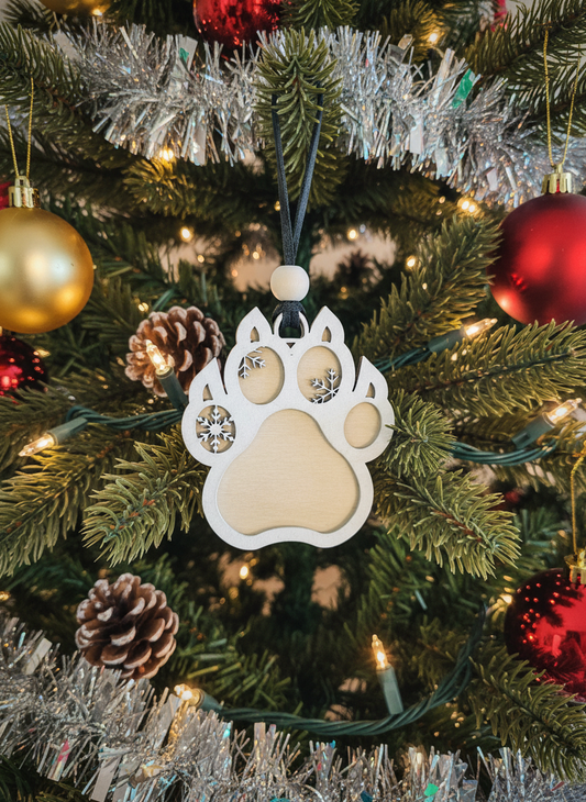 Wooden cat paw ornament hanging on a decorated Christmas tree with gold and red baubles