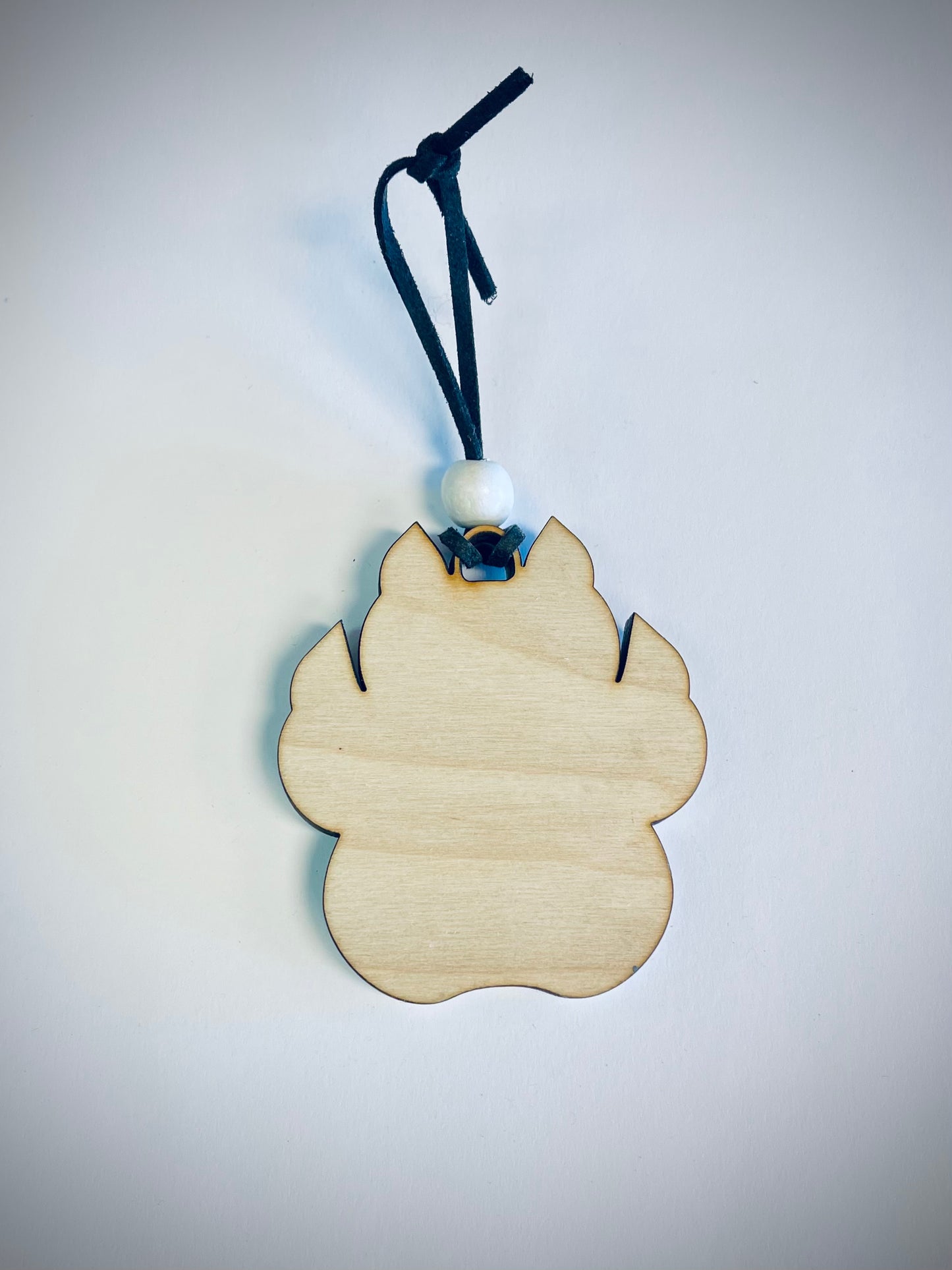 Wooden cat paw ornament with black string and white bead on white background