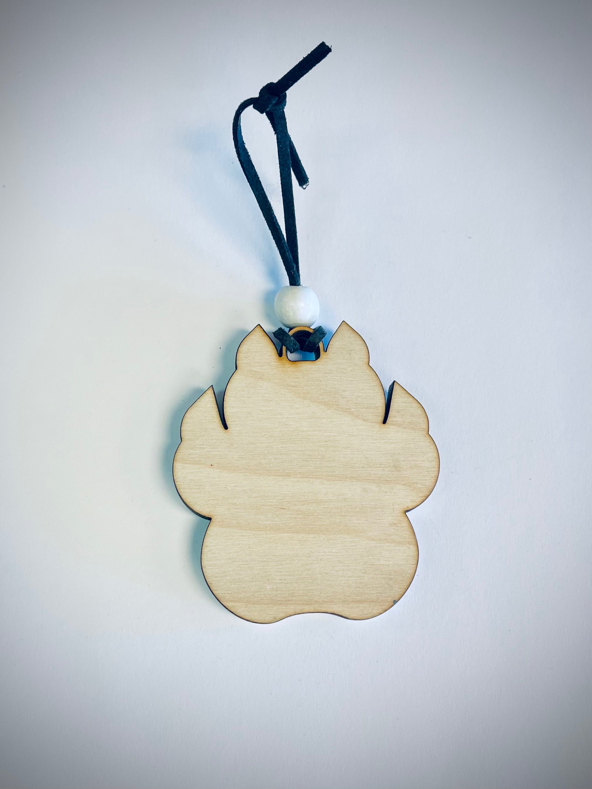 Wooden cat paw ornament with black string and white bead on white background