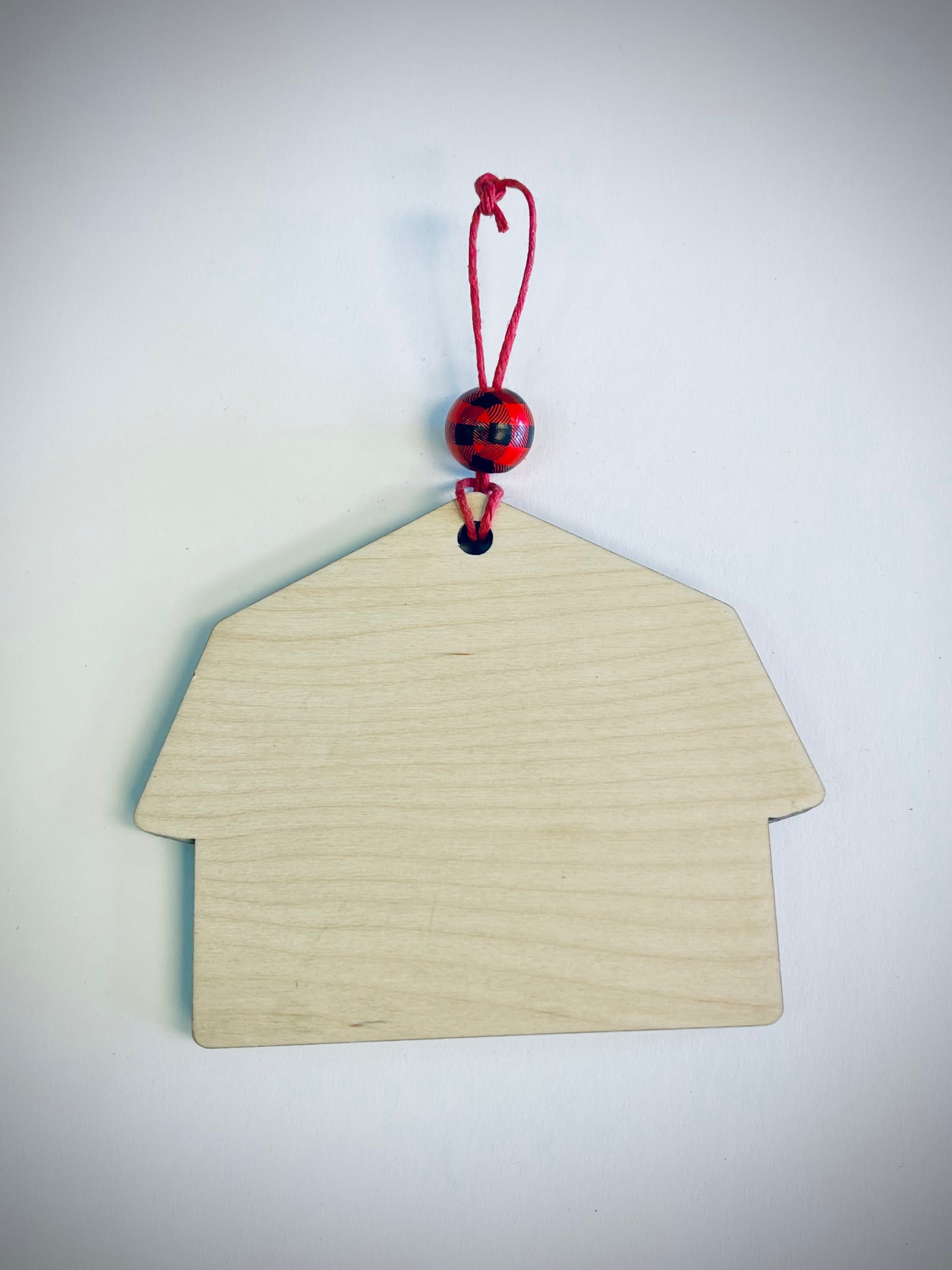 Blank wooden farmhouse ornament with red plaid bead and red string on white background