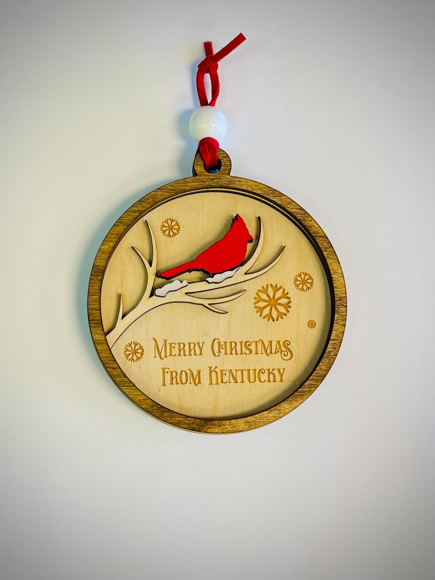 Wooden Christmas ornament with red cardinal on branch, 'Merry Christmas From Kentucky' text
