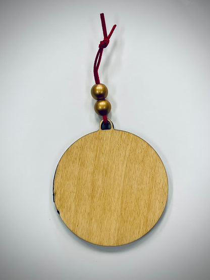 Round wooden ornament with gold beads and red cord on white background