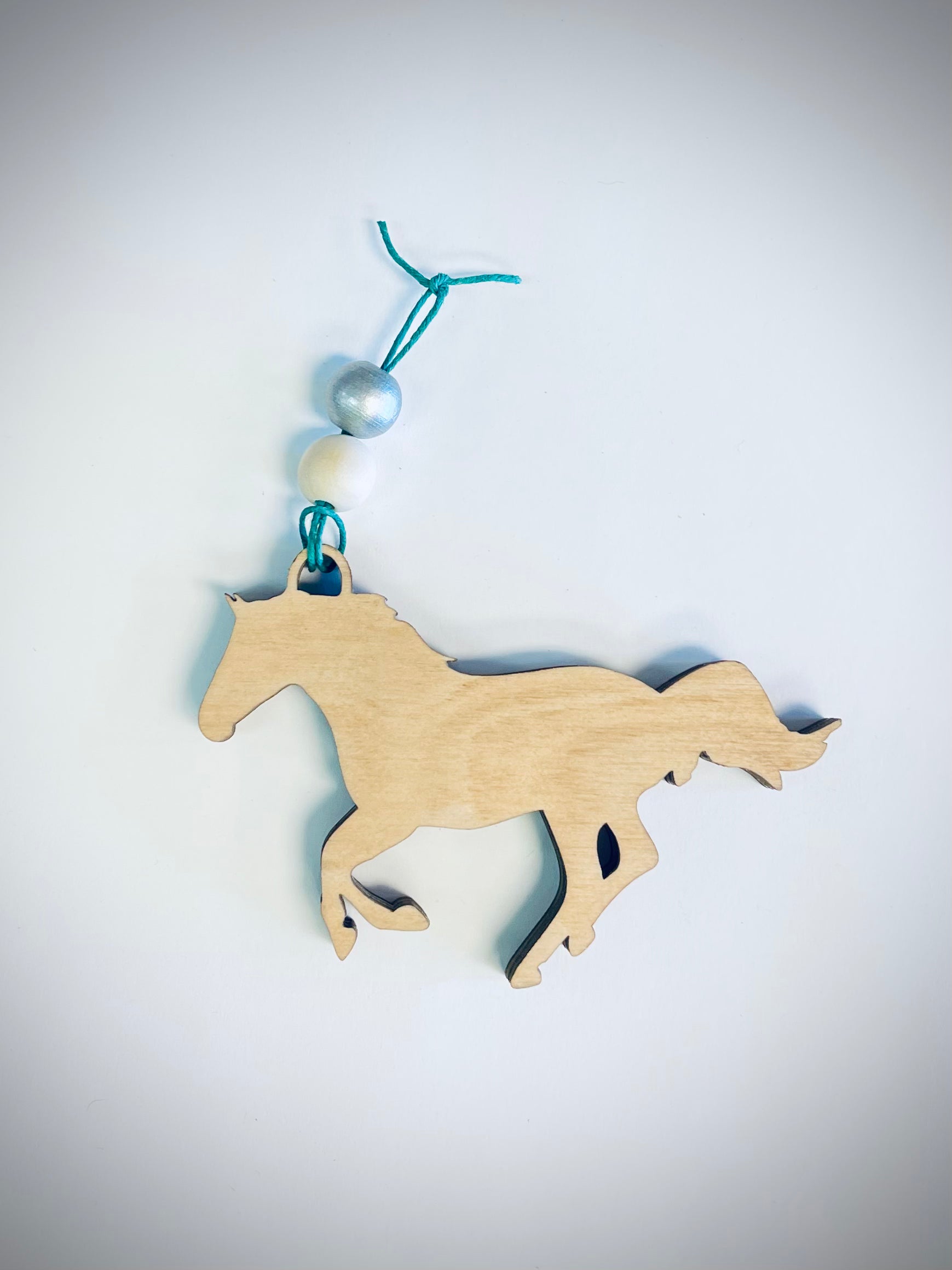 Layered wood horse ornament with blue and white beads on a teal string