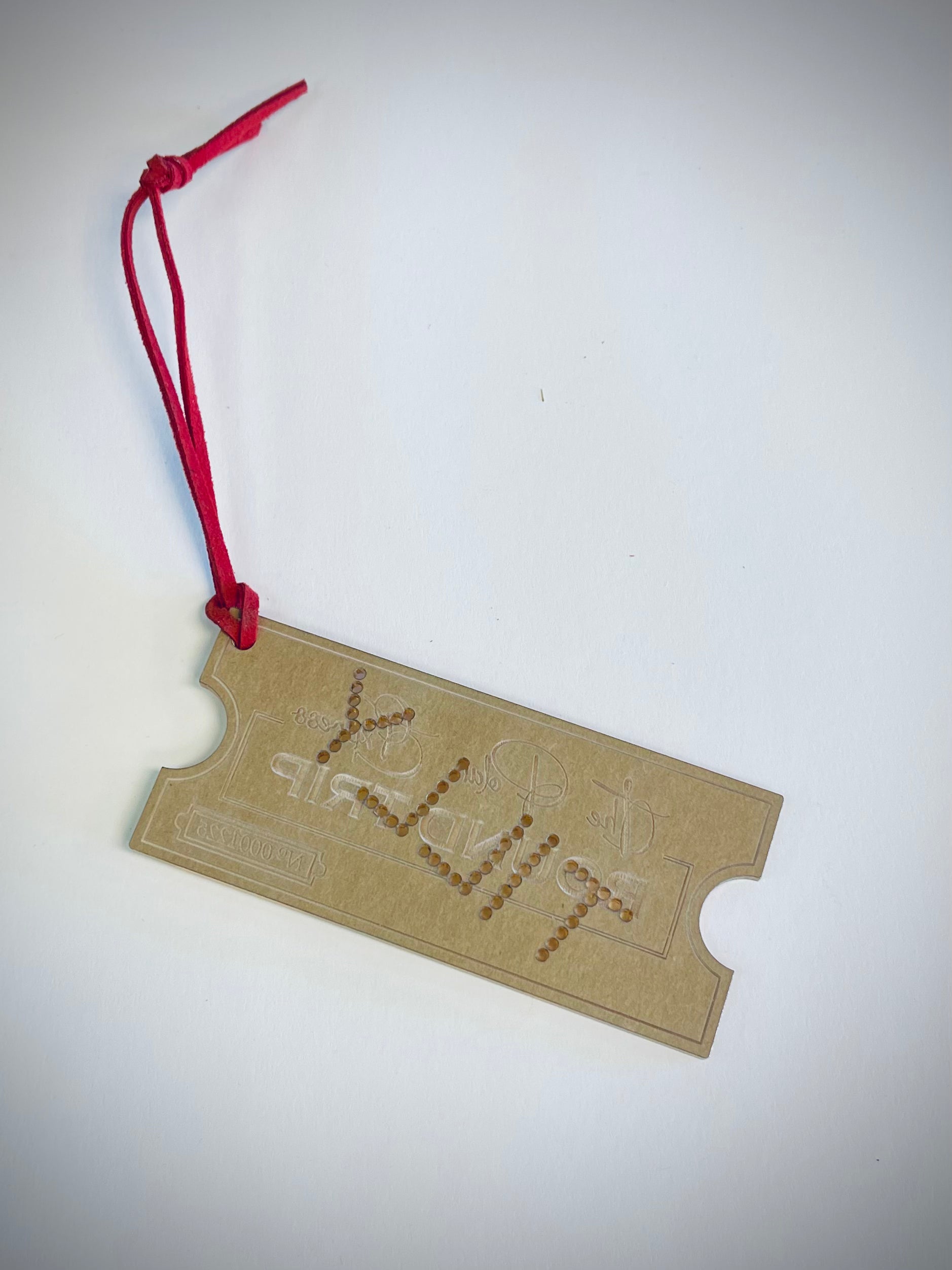 Polar Express ticket ornament with red string on white background