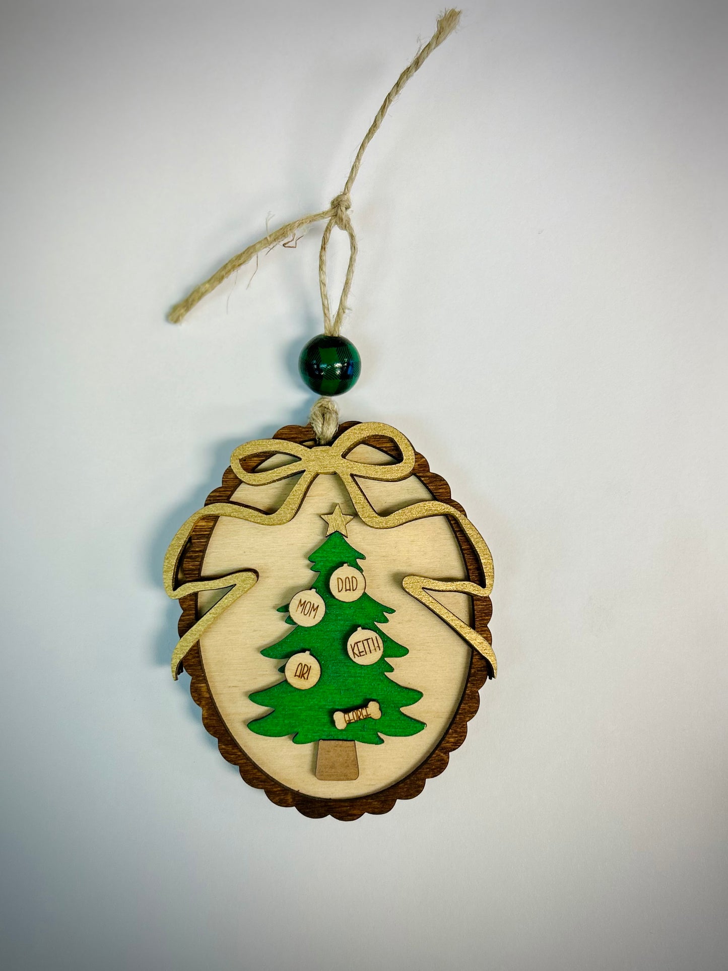 Wooden Christmas tree oval ornament with names, decorative bow, and string for hanging