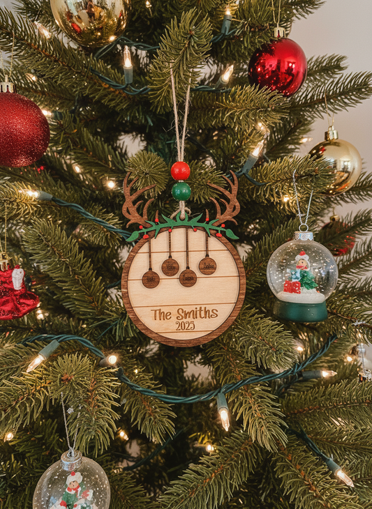 Personalized wooden deer family ornament on Christmas tree with lights and baubles