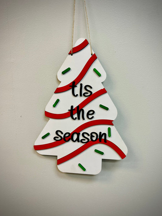 Christmas tree cake door hanger with red stripes, green sprinkles, and 'tis the season' text
