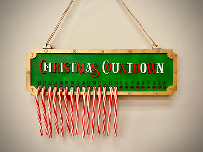 Christmas countdown sign with hanging candy canes on a green and gold background