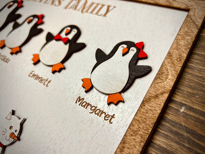Wooden penguin family plaque with cute penguin figures and engraved names on white background