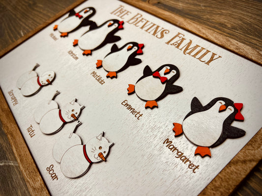 Custom wooden family plaque with penguin and cat figures, engraved names, rustic background
