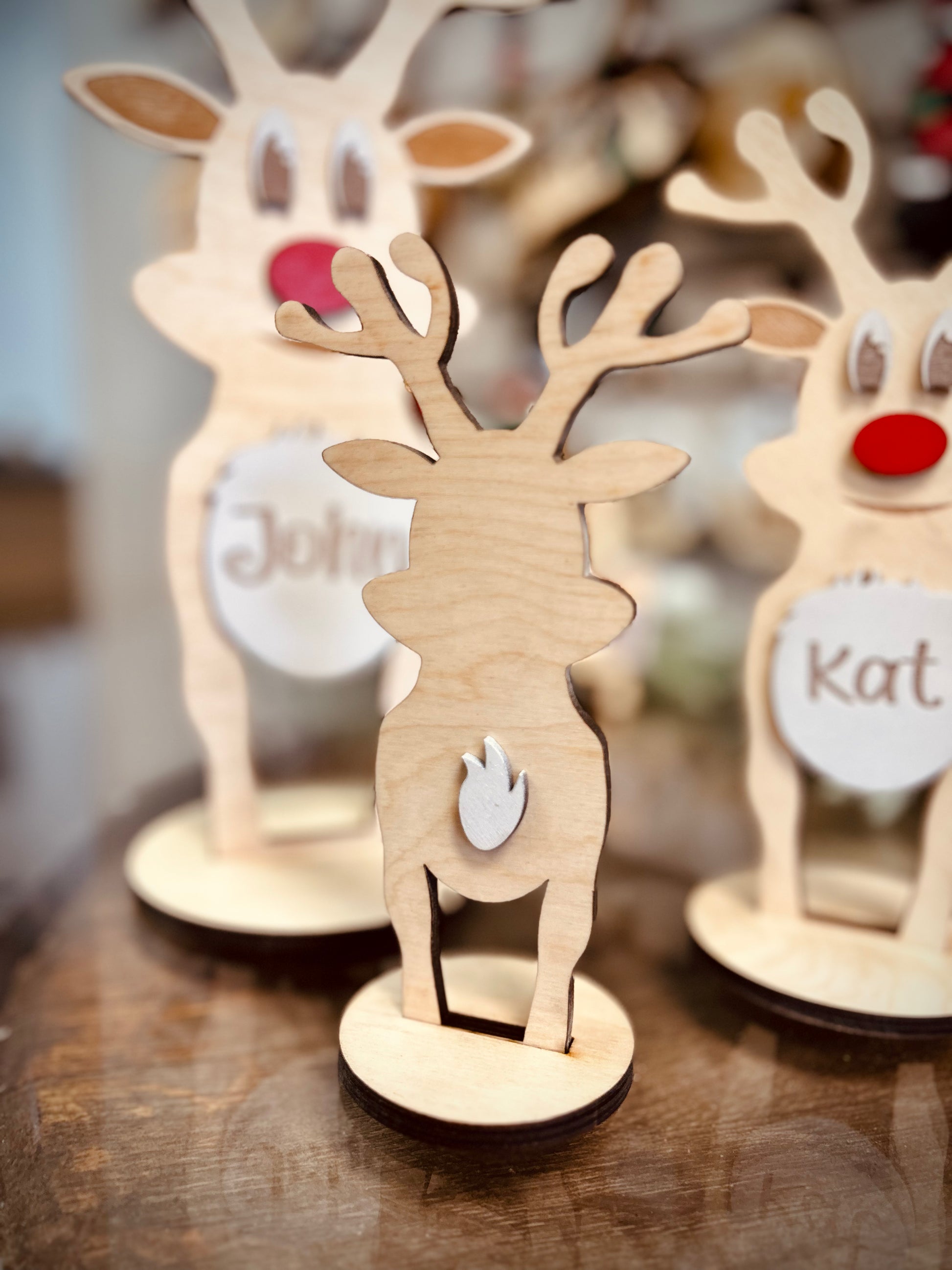 Wooden reindeer decorations with antlers and red noses on a wooden table