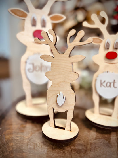 Wooden reindeer decorations with antlers and red noses on a wooden table