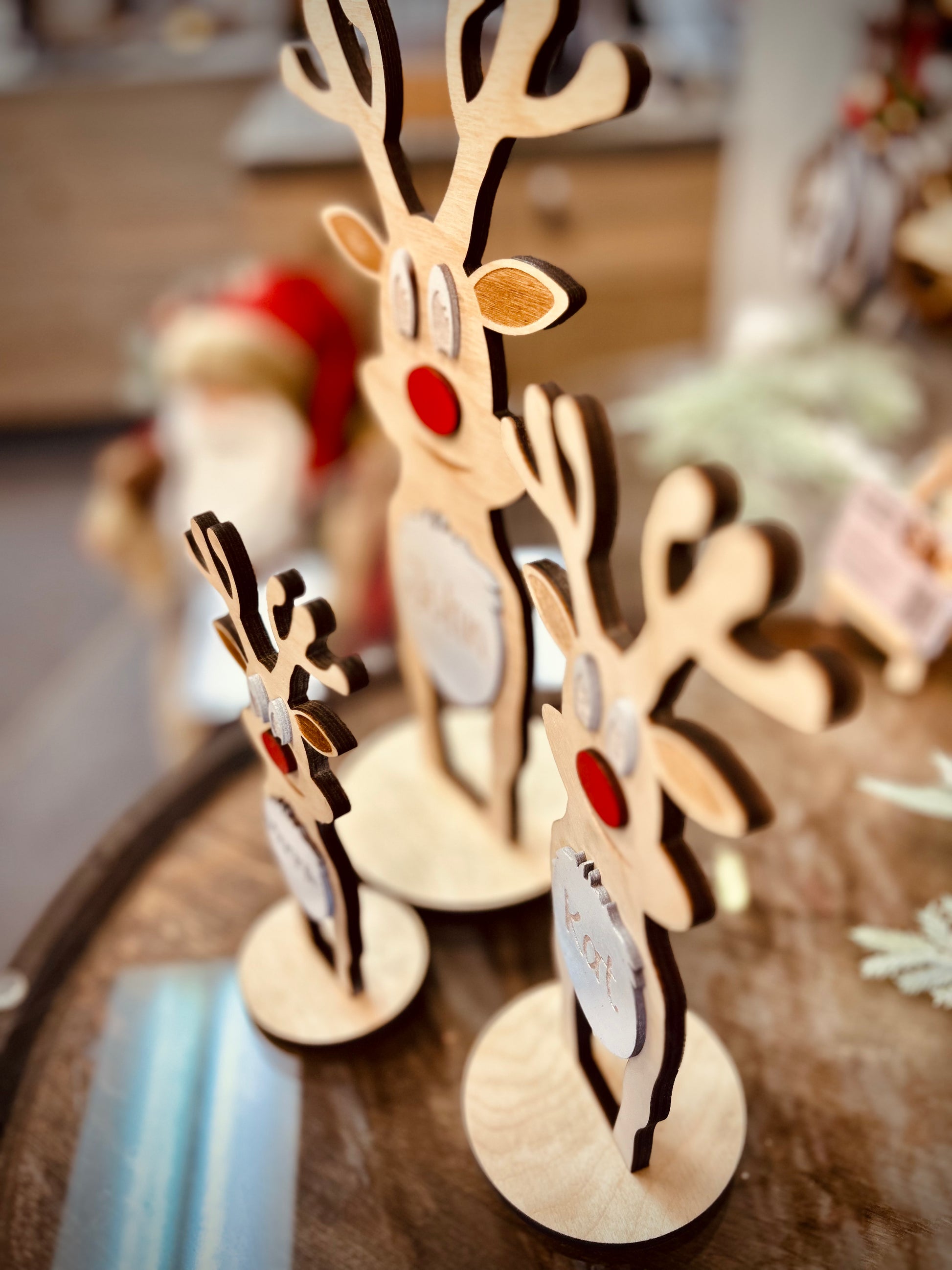 Wooden reindeer table decorations with red noses on a rustic wooden surface
