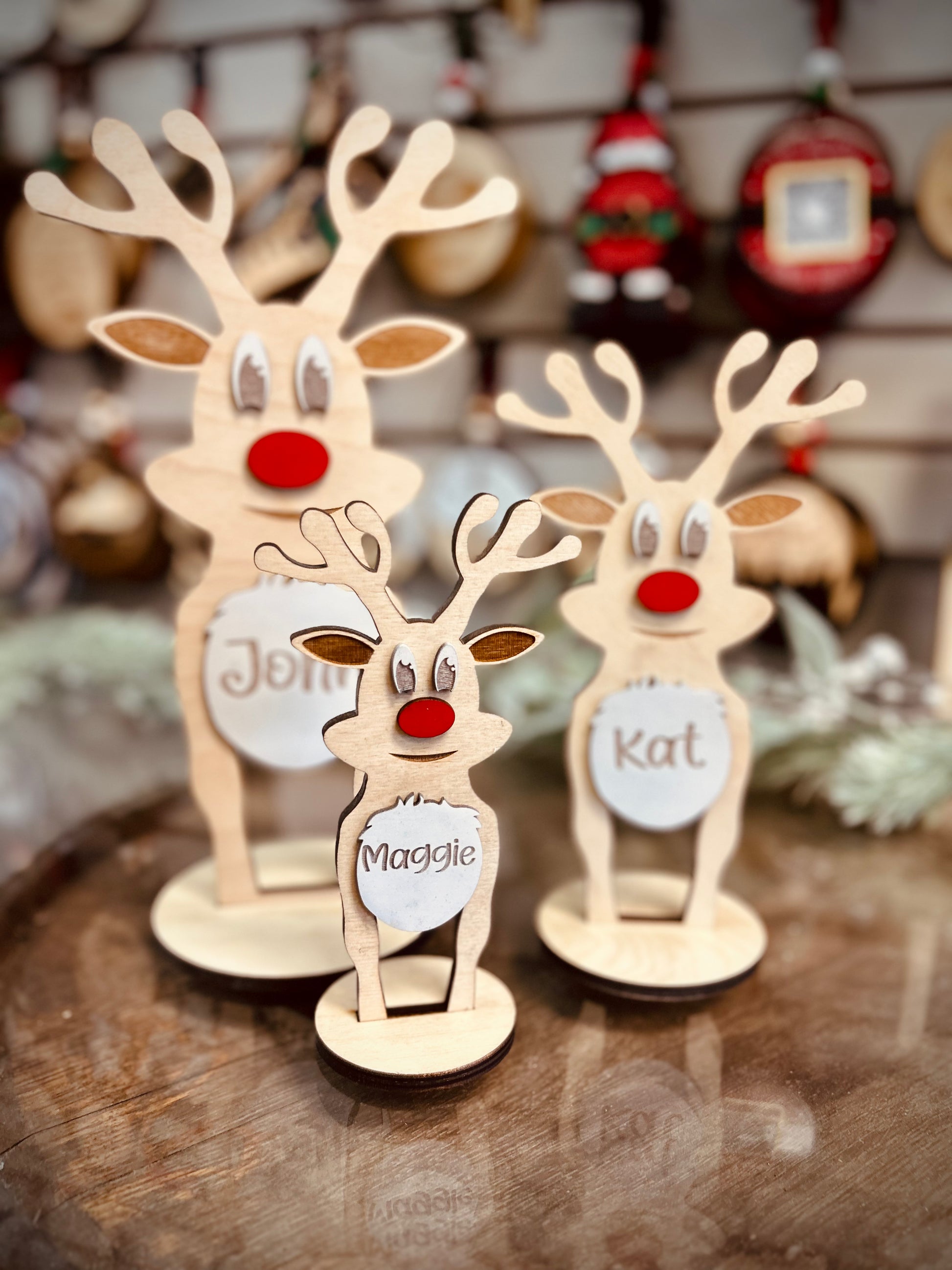 Personalized wooden reindeer decorations with red noses and custom name plaques on display.