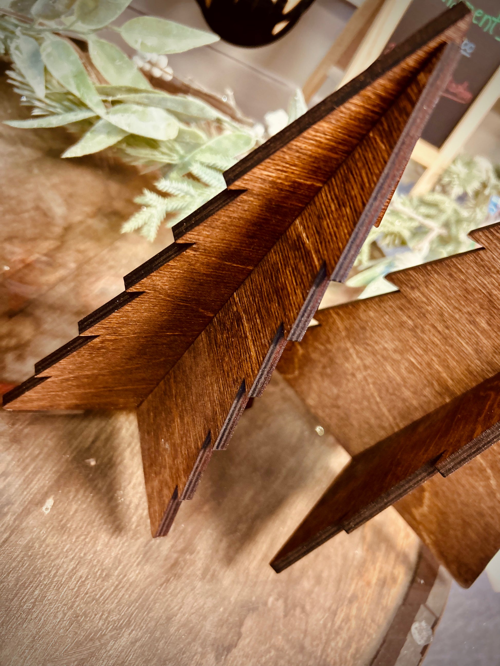 Wooden 3D Christmas tree decor on rustic table with greenery