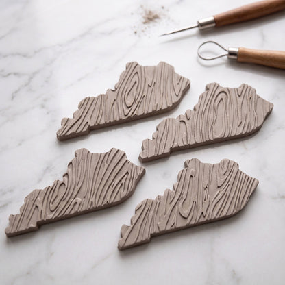 Custom engraved Kentucky-shaped wood grain decor pieces on marble surface